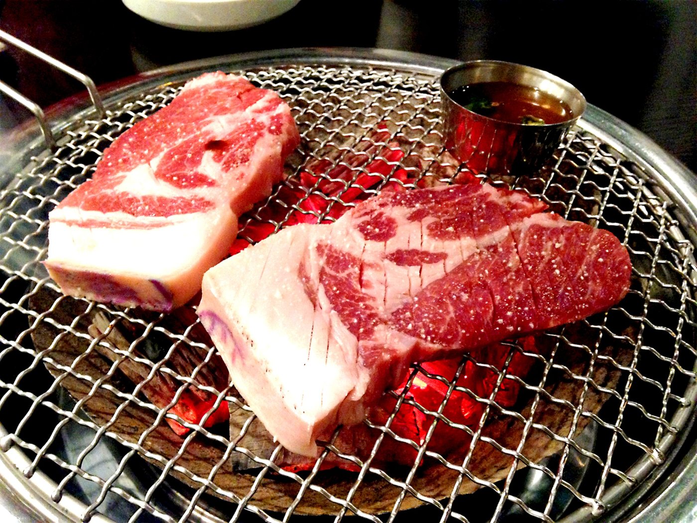 Thick cuts of pork on a charcoal grill at a Korean BBQ restaurant
